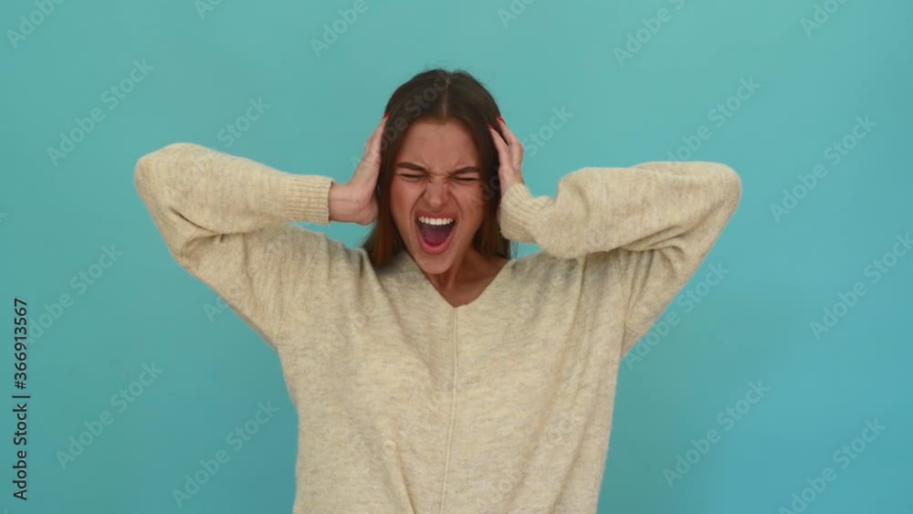 angry woman screaming holding her head isolated on blue background