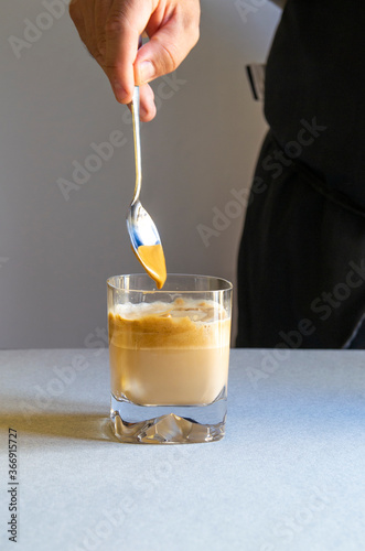 A person preparing a Dalgona coffee, Thai coffee. Refreshing summer drink photo