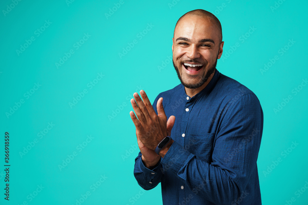Joyful dark-skinned man laughing against turquoise background Joyful dark-skinned man laughing against turquoise background