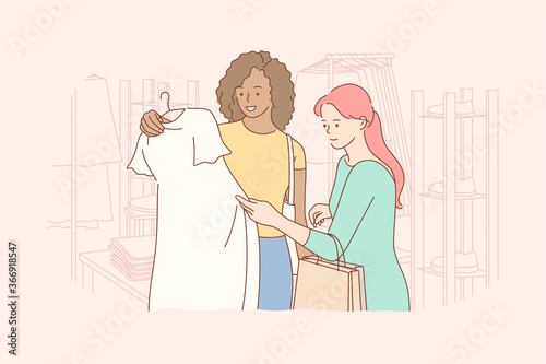 Friendship, shopping, recreation, fashion, beauty concept. Young woman and african american girl friends customers choosing swapping trendy clothes at shop. Consumption and stuff exchage buying dress. photo