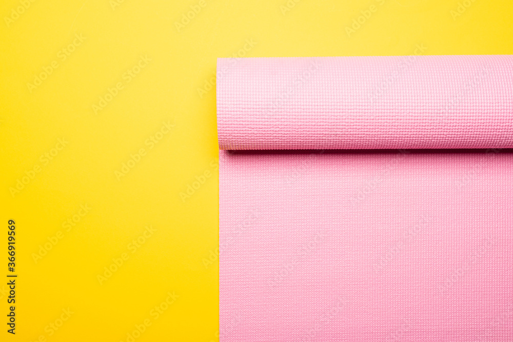 top view of pink fitness mat on yellow background top view of pink fitness mat on yellow background