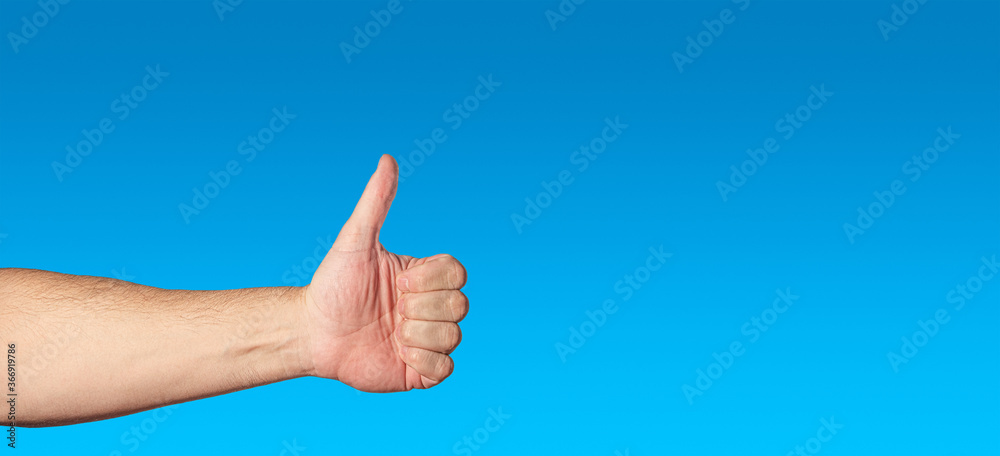 Man’s naked hand showing a gesture thumb up, as a like or agreement isolated at blue gradient background as blue sky with copy space for text. Man’s naked hand showing a gesture thumb up, as a like or agreement isolated at blue gradient background as blue sky with copy space for text.