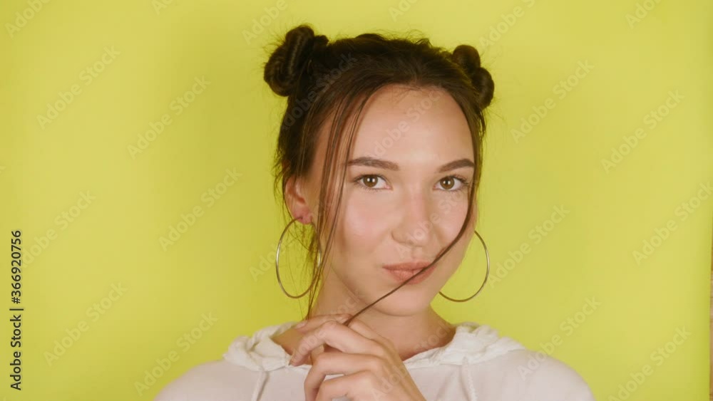 Happy woman looking at the camera, playing her hair and smiling. Isolated yellow background. High quality 4k footage Happy woman looking at the camera, playing her hair and smiling. Isolated yellow background. High quality 4k footage