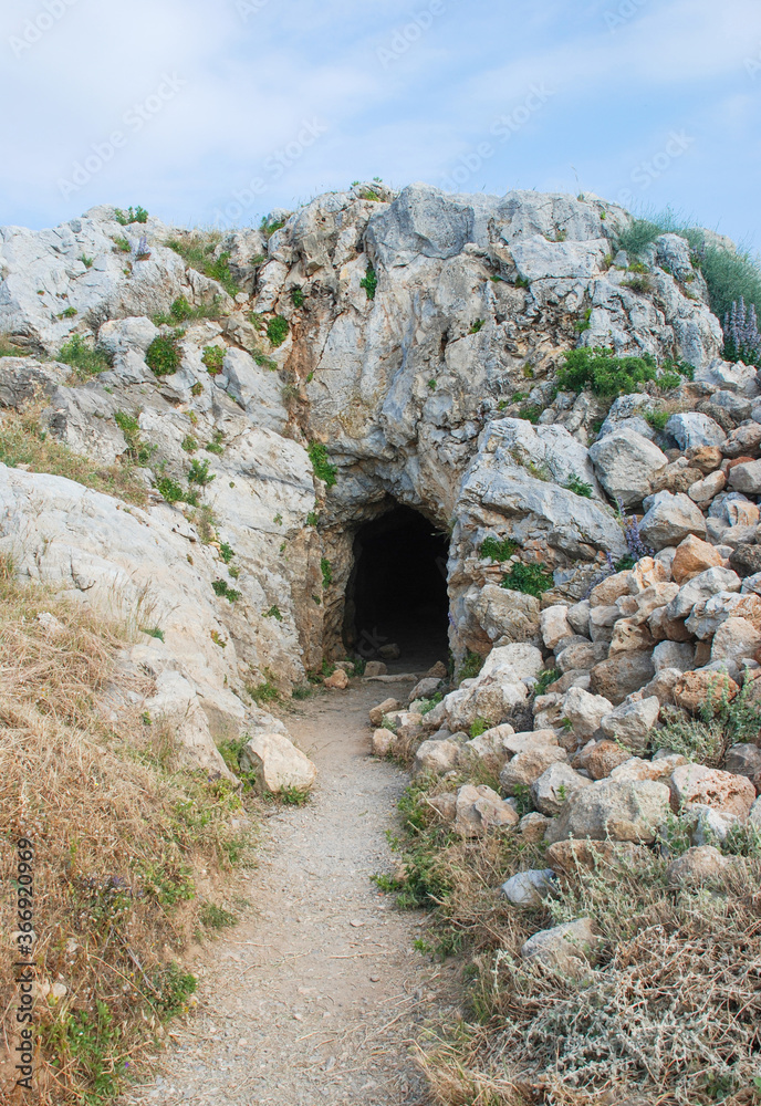 The path to the entrance to a dark rocky cave, rock, grotto.