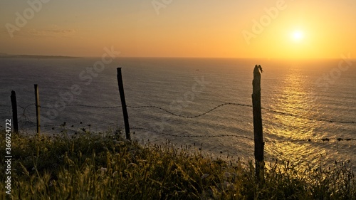 Barbed wire in front of the ocean at sunset 