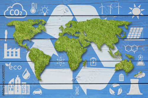 Green grass World Map, white recycling symbols and ecology icons on blue wood backdrop. Ecology concept background.
