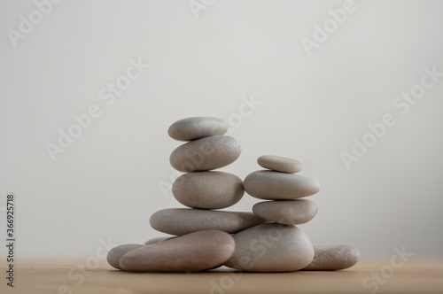Simplicity stones cairns isolated on white background  group of light gray pebbles built in towers  wood table
