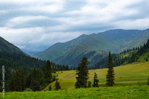 Green mountain valley with clouds. Adventure travel. Outdoor landscape. Summer vacation travel concept. Kazakhstan mountains, Tekes river valley. Tourism in Kazakhstan concept.