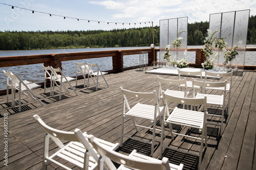 Beautiful wedding ceremony place on the lake with natural materials in white color