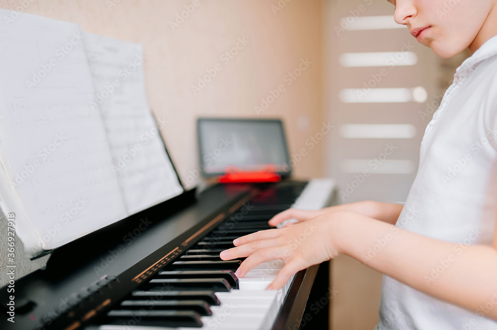 Fototapeta Dość młody muzyk grający w domu na klasycznym pianinie cyfrowym podczas zajęć online w domu, dystans społeczny podczas kwarantanny, samoizolacja, koncepcja edukacji online