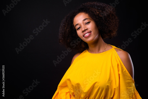 Young beautiful African woman with Afro hair against black background