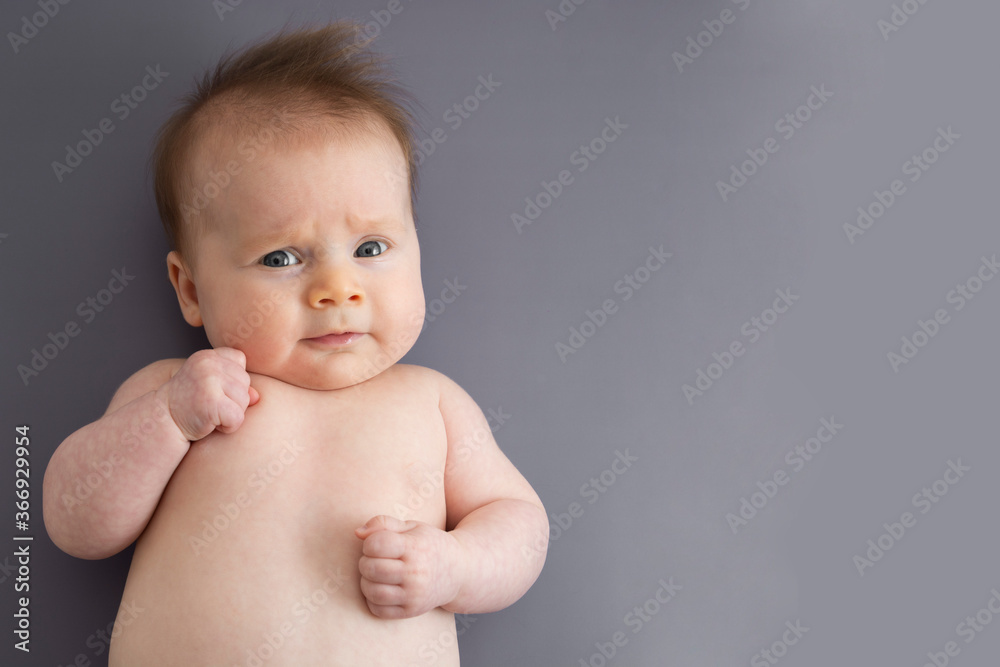 Newborn baby lying over gray background. Newborn baby skin care. Copy space. Newborn baby lying over gray background. Newborn baby skin care. Copy space.