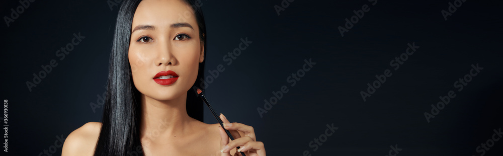 Young woman applying lipstick with an applicator Young woman applying lipstick with an applicator