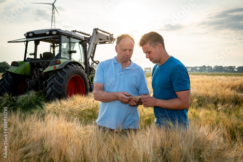 Ackerbau - Düngeverordnung, Landwirt und sein Sohn stehen im heranreifendem Getreidefeld. photo