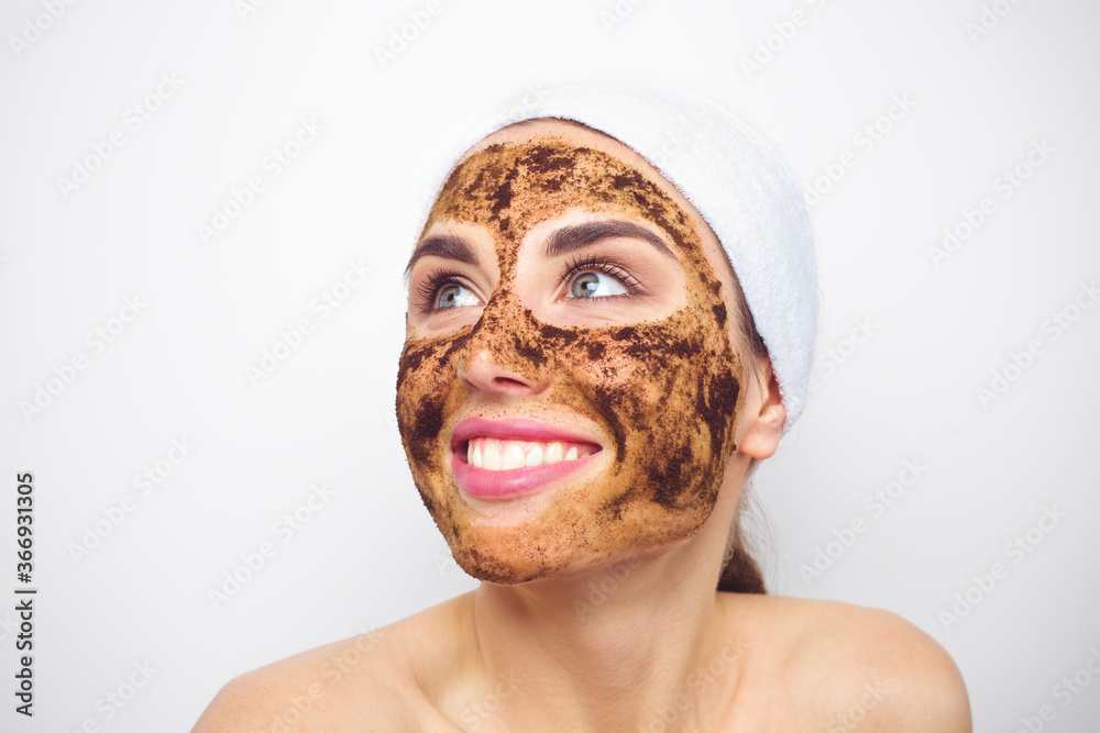Coffee grounds on the face of a smiling young woman. Scrubbing. Facial cleansing in a beauty salon. Coffee grounds on the face of a smiling young woman. Scrubbing. Facial cleansing in a beauty salon.