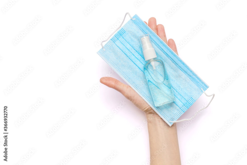Female hands holding liquid soap or hand sanitizer spray dispenser and medical protective mask isolated on white background with clipping path Female hands holding liquid soap or hand sanitizer spray dispenser and medical protective mask isolated on white background with clipping path