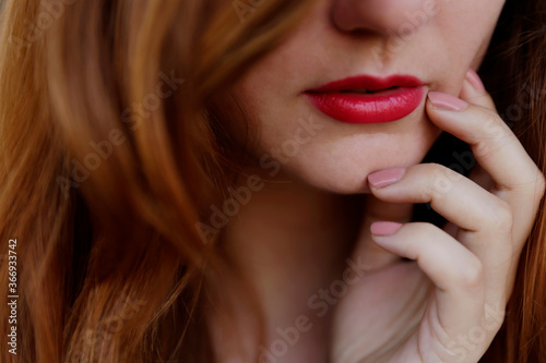 Sensual portrait of young redhead woman. Close up on lips with red lipstick. Sensual portrait of a woman. 