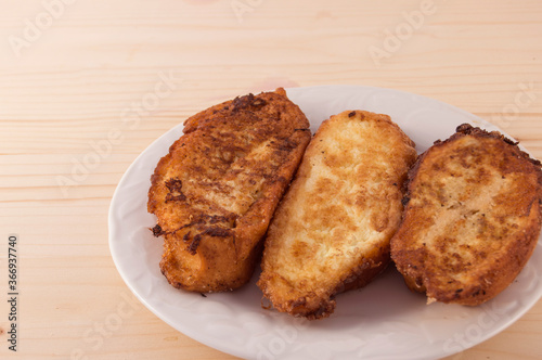 Plate with three Torrijas Spanish french toast isolated on white background