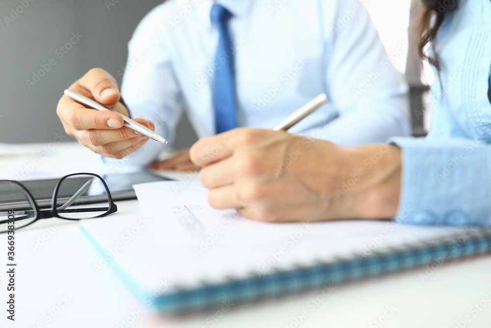 Female and male hands hold pens in office over documents. Small and medium business development concept Female and male hands hold pens in office over documents. Small and medium business development concept