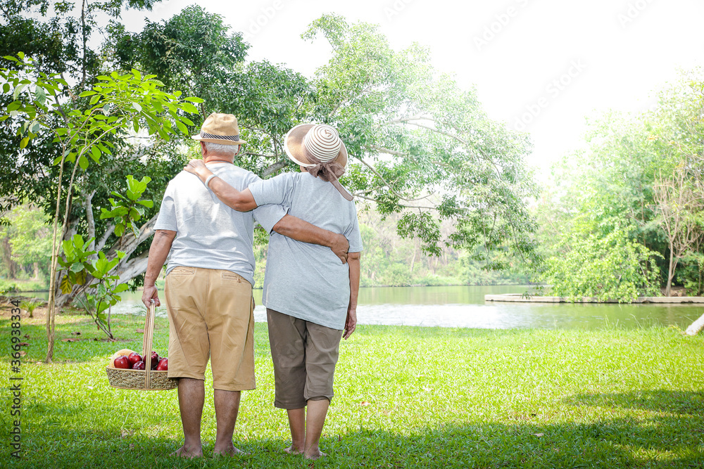Elderly Asian couple walking together And carrying fruit baskets in a public park Enjoy life after retirement. Elder health concept. Copy space Elderly Asian couple walking together And carrying fruit baskets in a public park Enjoy life after retirement. Elder health concept. Copy space