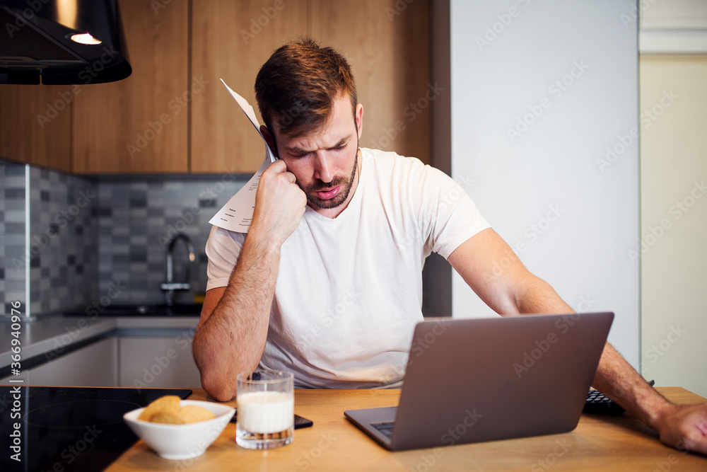 Worried man paying bills online at home Worried man paying bills online at home