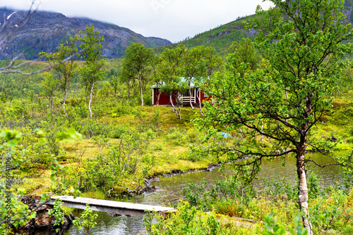 Norwegian wooden cabin hidden in a forest. These types of huts are mainly used for tourists or fishermen. Nowdays they are popular weekend gataway from the city to countryside areas. photo