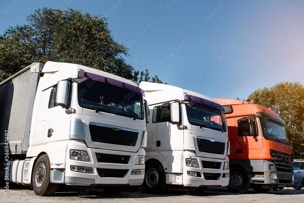 Lateral view of trucks staying in the truck parking on the sunset. Lateral view of trucks staying in the truck parking on the sunset.