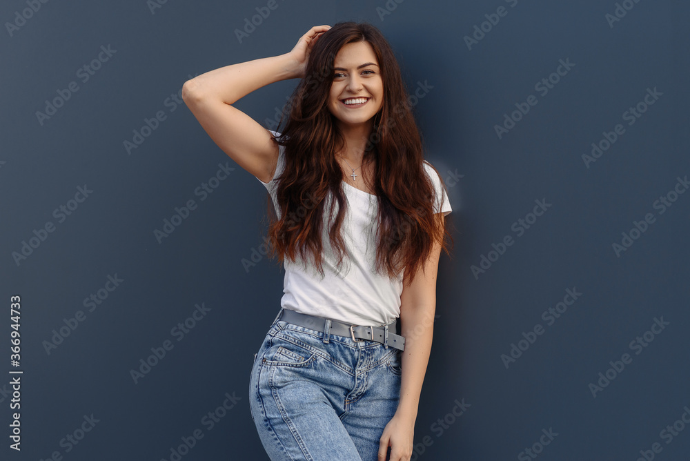 Portrait of smiling pretty girl. Beautiful young woman with backpack posing on a blue wall Portrait of smiling pretty girl. Beautiful young woman with backpack posing on a blue wall