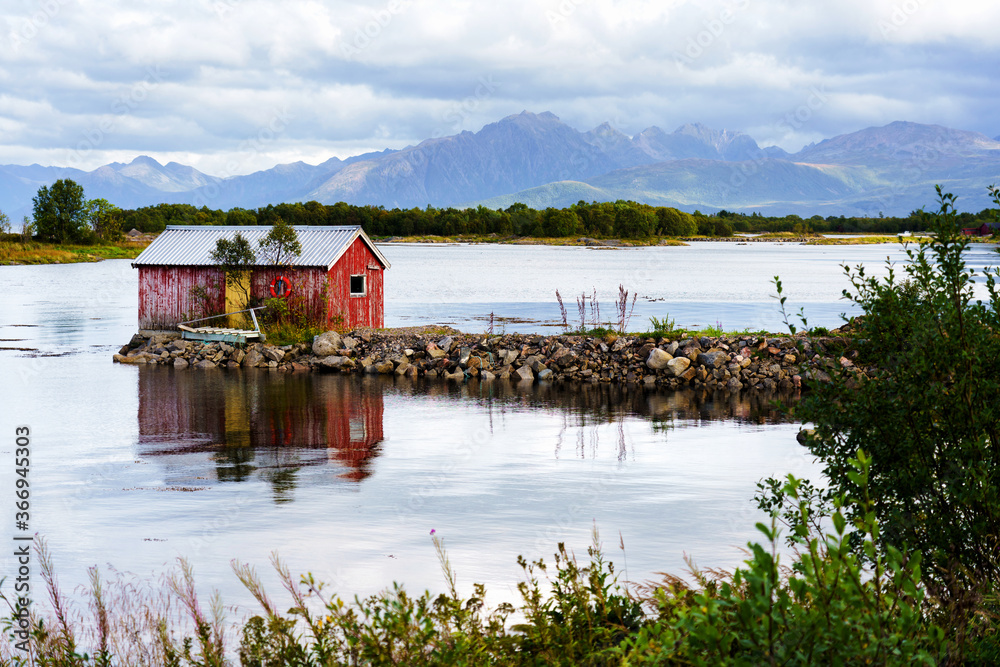 Norwegian coast landscape with a typical red house. Wooden red houses are called rorbu or rorbuer and are used for fishermen or tourists. Lofoten, Norway