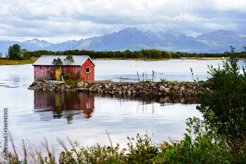 Obraz na płótnie Norwegian coast landscape with a typical red house. Wooden red houses are called rorbu or rorbuer and are used for fishermen or tourists. Lofoten, Norway w salonie