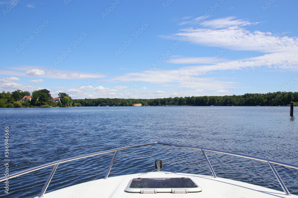 Boating on Peetz lake (Peetzsee) in Gruenheide in federal state Brandenburg, with the sand beach in background, Germany