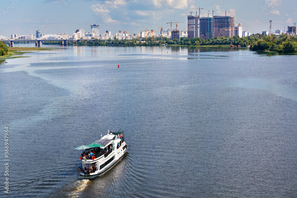 A river tram carries tourists along the Dnipro River along the left bank of Kyiv, top view.