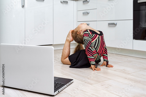 baby does gymnastics at home online. does exercises in front of a laptop photo