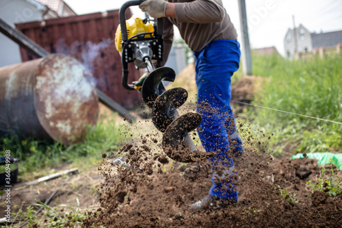 A worker is drilling soil for a gate