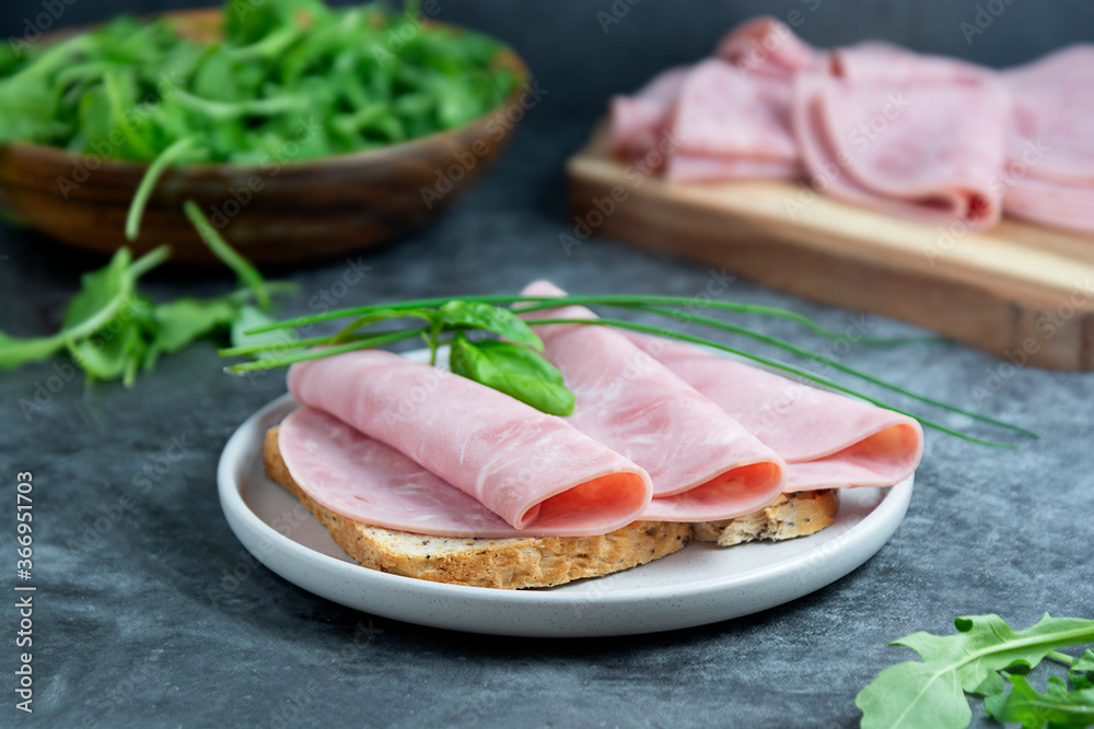 Ham sandwich. Pork ham slices over wholegrai bread over dark background.