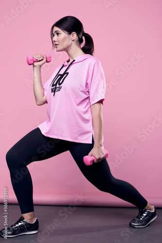 ?orgeous body positive Latin woman in a pink hoodie with dumbbells photo