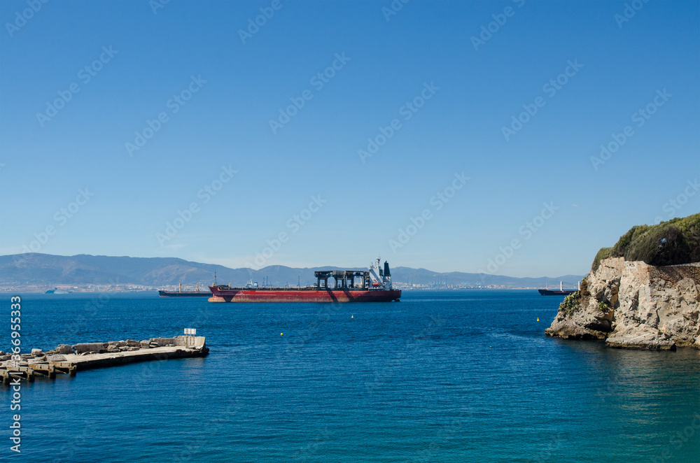 Small blue bay and empty cargo ship on the horizon, Gibraltar.