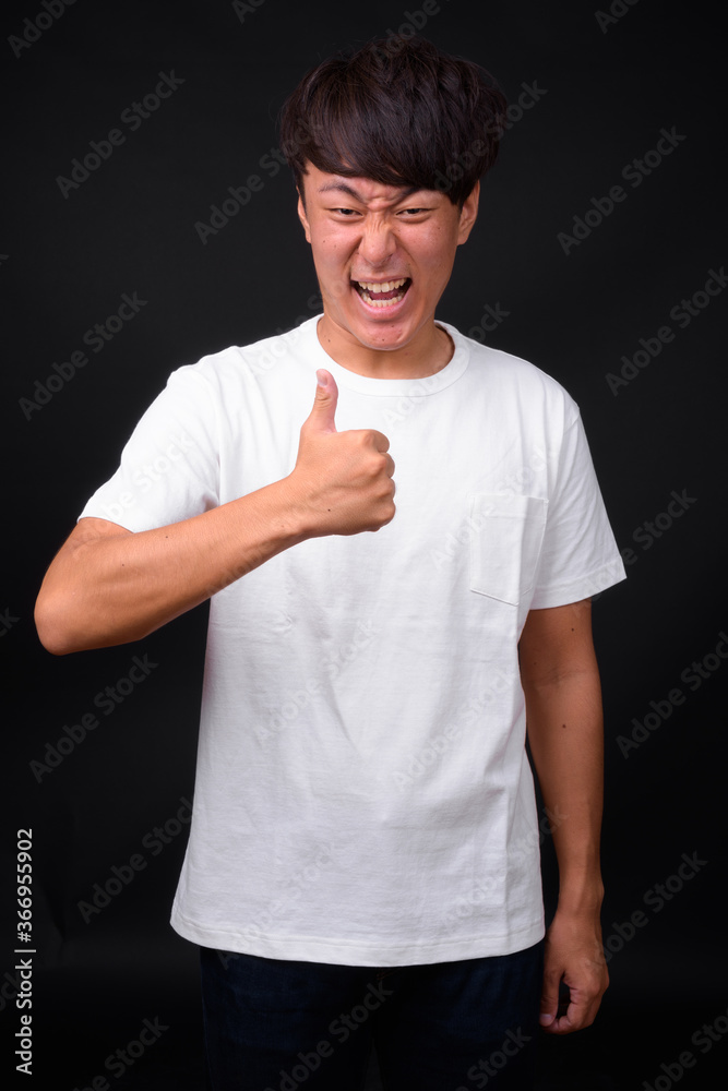 Young handsome Asian man against black background Young handsome Asian man against black background