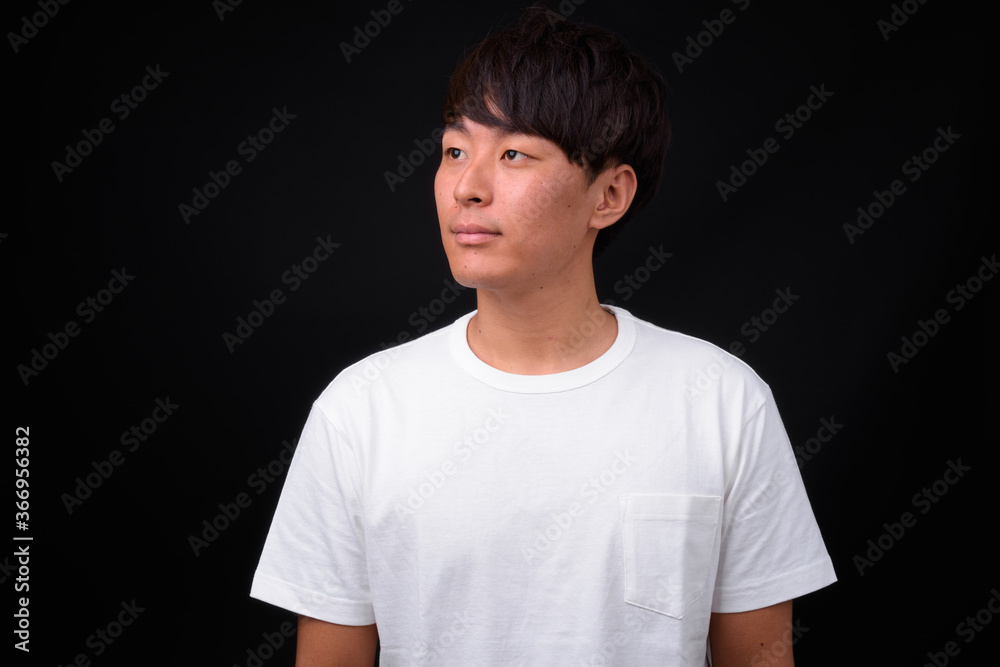 Young handsome Asian man against black background Young handsome Asian man against black background