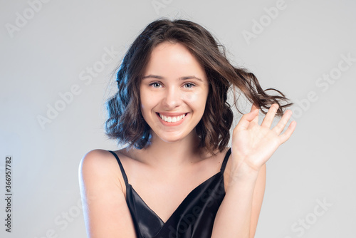  close-up portrait of a beautiful girl in the studio. smiling brunette on gray background