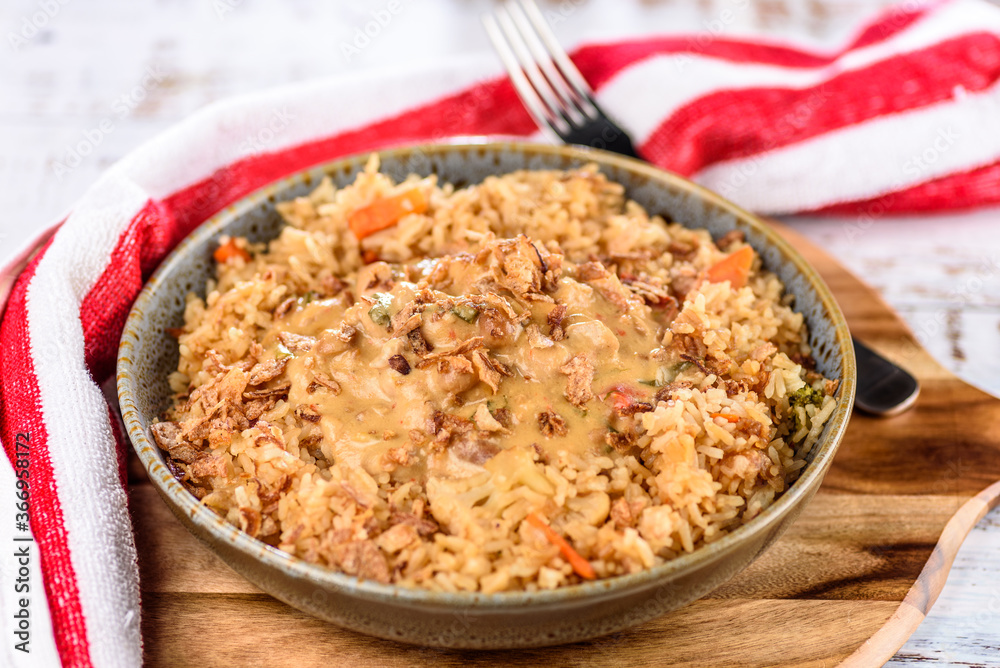 A bowl of satay chicken with fried rice on a wooden board and red napkin A bowl of satay chicken with fried rice on a wooden board and red napkin