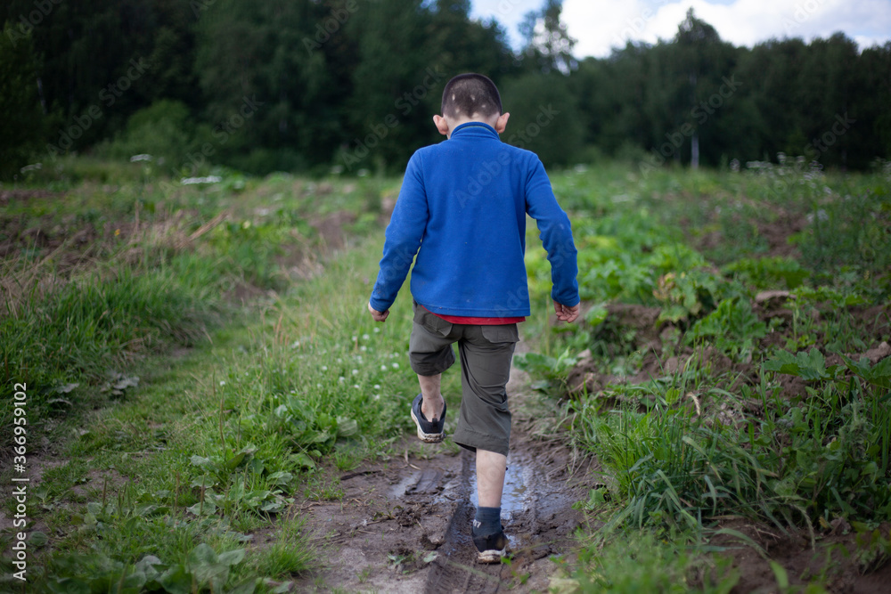 The child is walking in a puddle. The child is walking in a puddle.