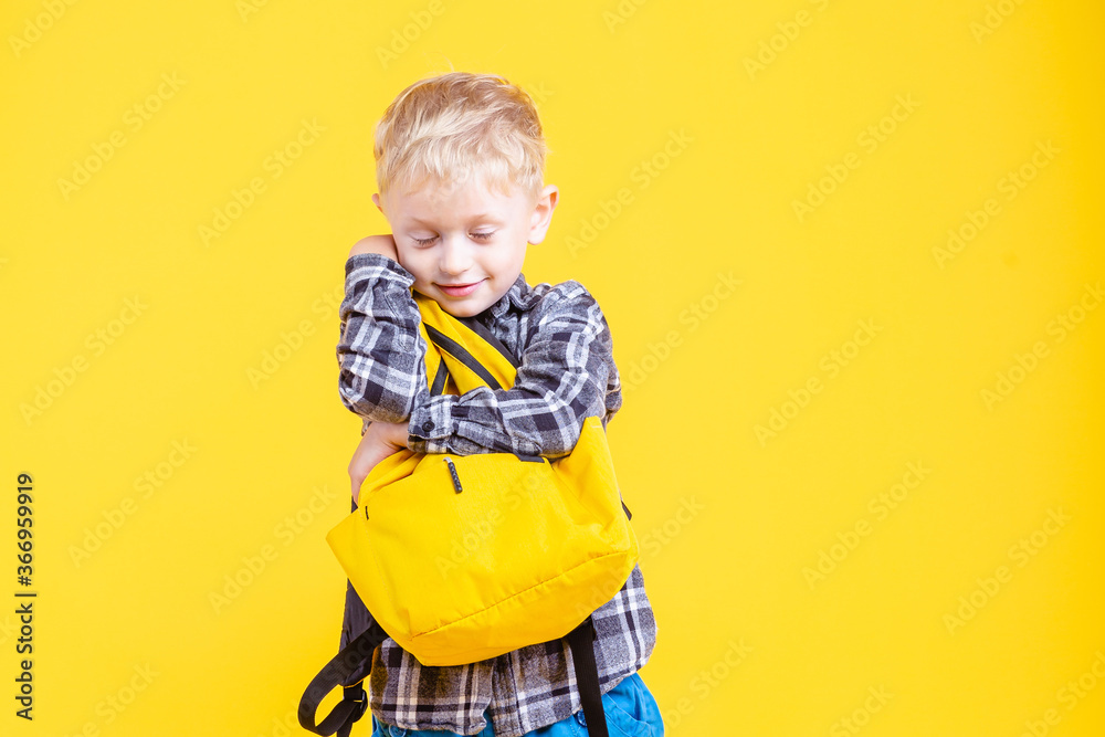 schoolboy holding backpack isolated on yellow. schoolboy holding backpack isolated on yellow.