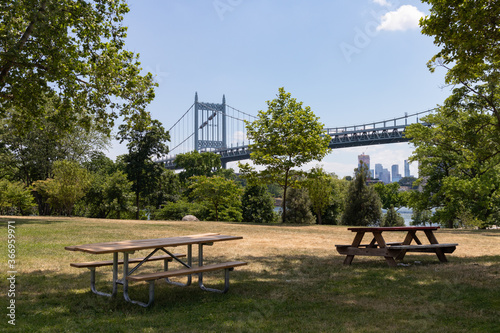 Empty Picnic Tables and a Grass Field with Trees and the Triborough Bridge in the background during Summer at Randalls and Wards Islands in New York City photo