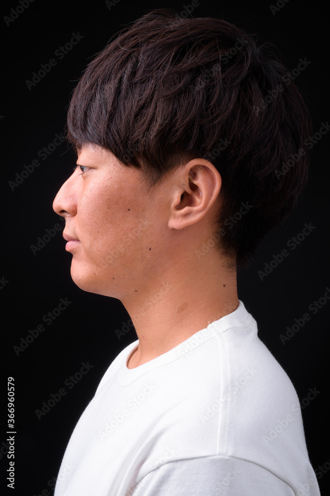 Young handsome Asian man against black background Young handsome Asian man against black background