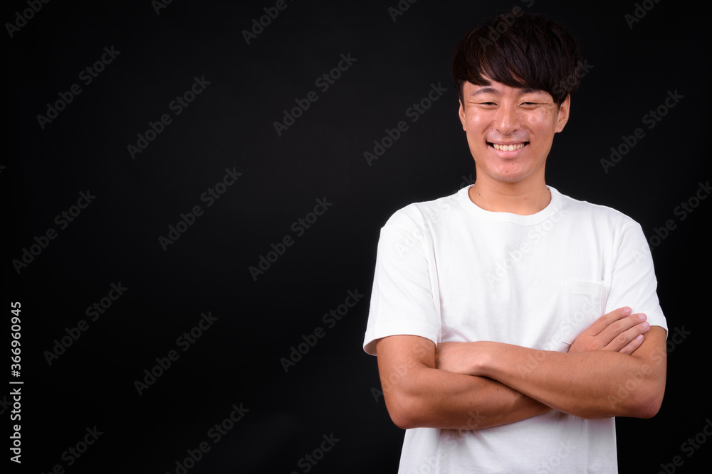 Obraz premium Young handsome Asian man against black background
