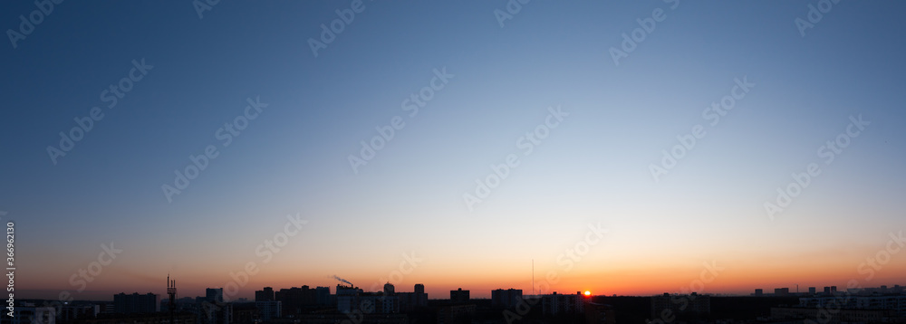 Clear blue sky and sun over city, sunset panorama