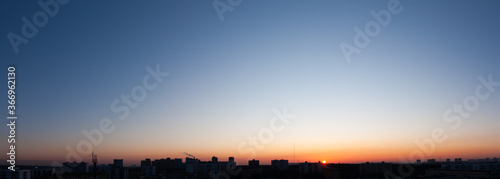 Clear blue sky and sun over city  sunset panorama