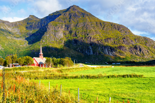 Flakstad Church with mountains in the background, exquisite XVIII century baroque masterpiece in the Arctic, Flakstadoy, Lofoten Islands, North of the Arctic Circle, Norway photo