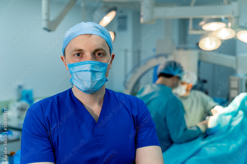 Portrait of a doctor or medical specialist. Vertical portrait. Man in scrubs. Light background with operating room. Closeup. Portrait of a doctor or medical specialist. Vertical portrait. Man in scrubs. Light background with operating room. Closeup.